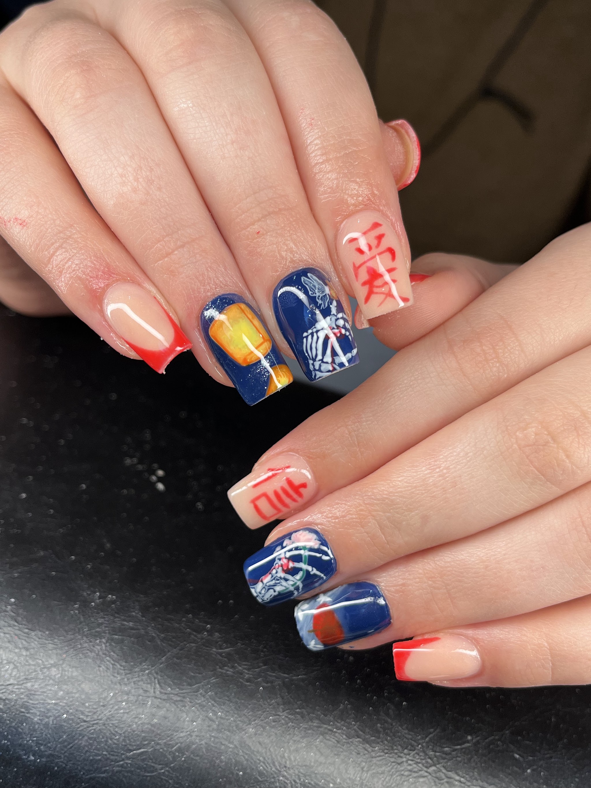 Vierkante nagels met illustraties in blauw en oranje, een rood teken en rode french tips