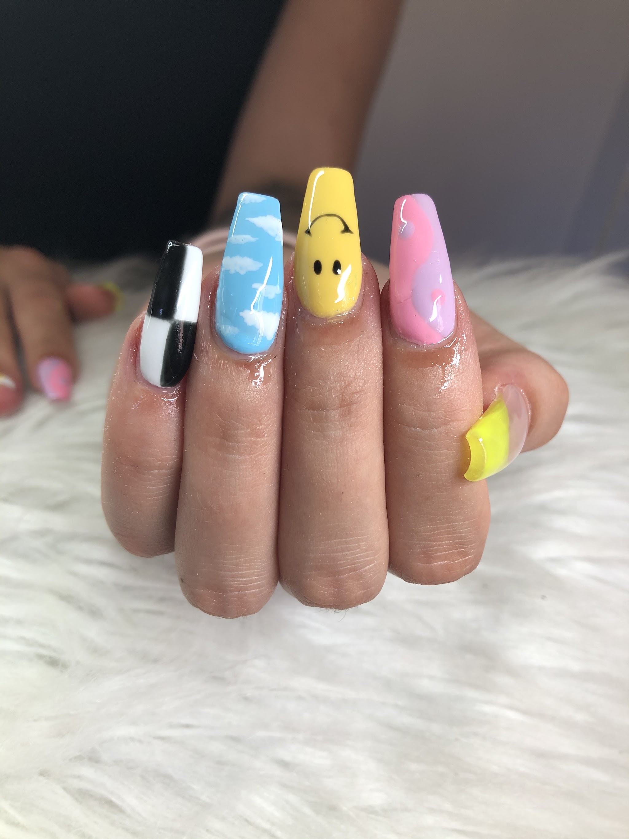 Lange coffin nagels met checkerboard, wolkjes, een gele smiley en roze swirl