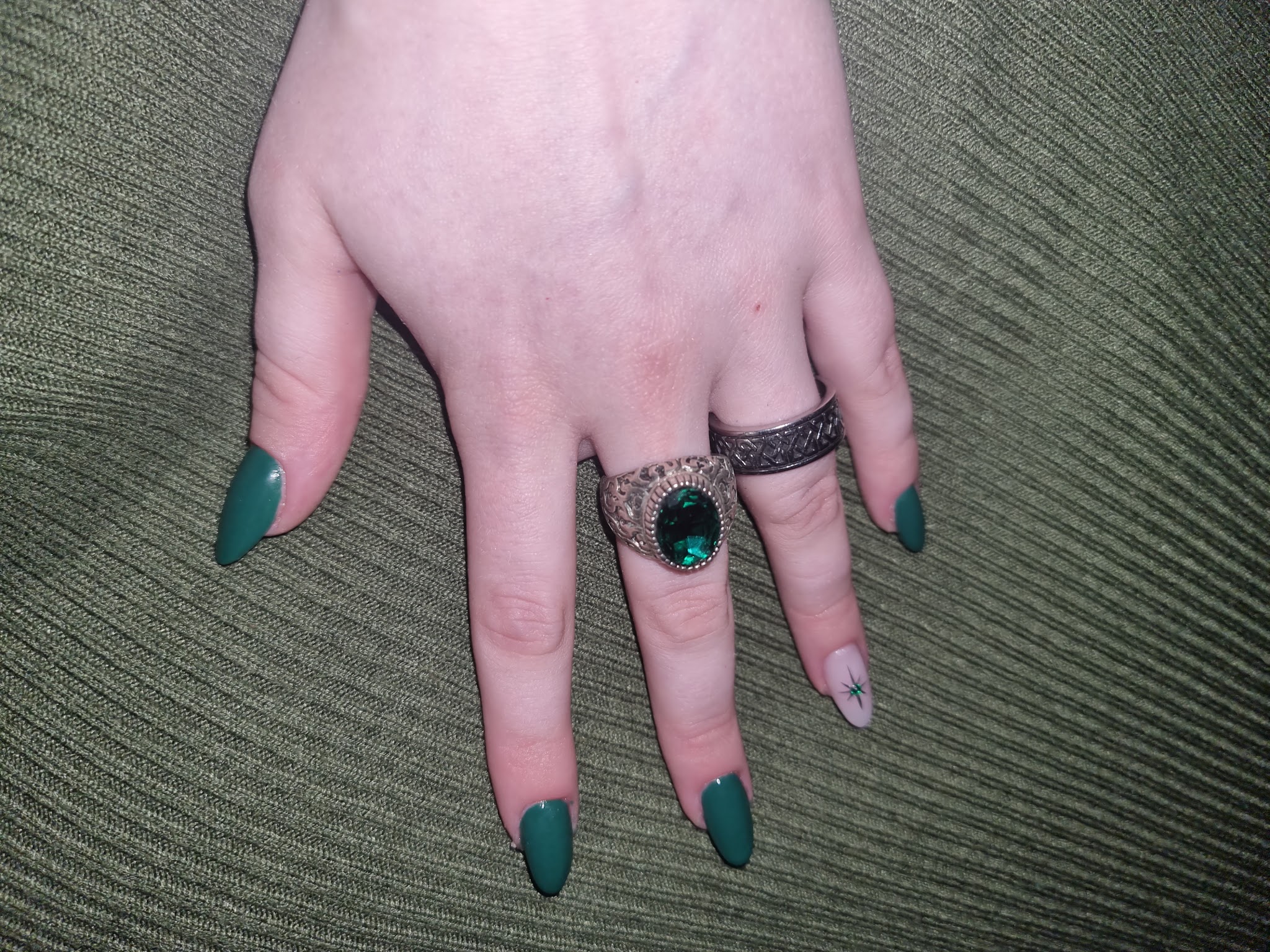 Korte donkergroene amandelnagels met een klein sterretje